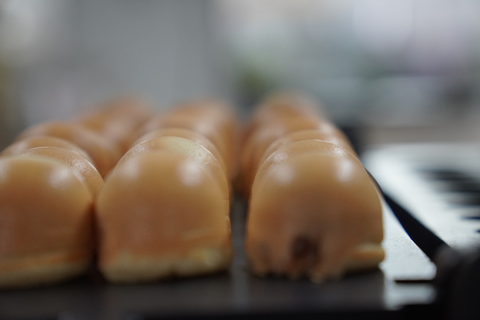 Close-up of several rounded, brown pastries made with a kayaball machine, arranged in neat rows on a tray against a blurred background.