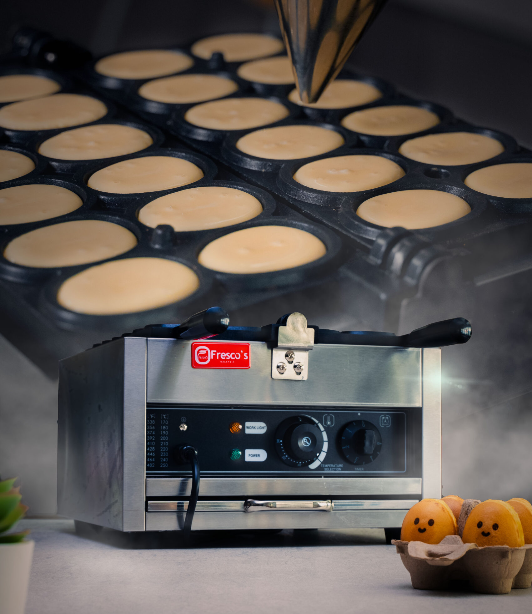 A Fresco Malaysia Waffle Machine sits on a countertop with a mold of batter above it and egg-shaped pastries decorated with smiling faces—perfect for those looking to start a small food business or run a profitable snack business.