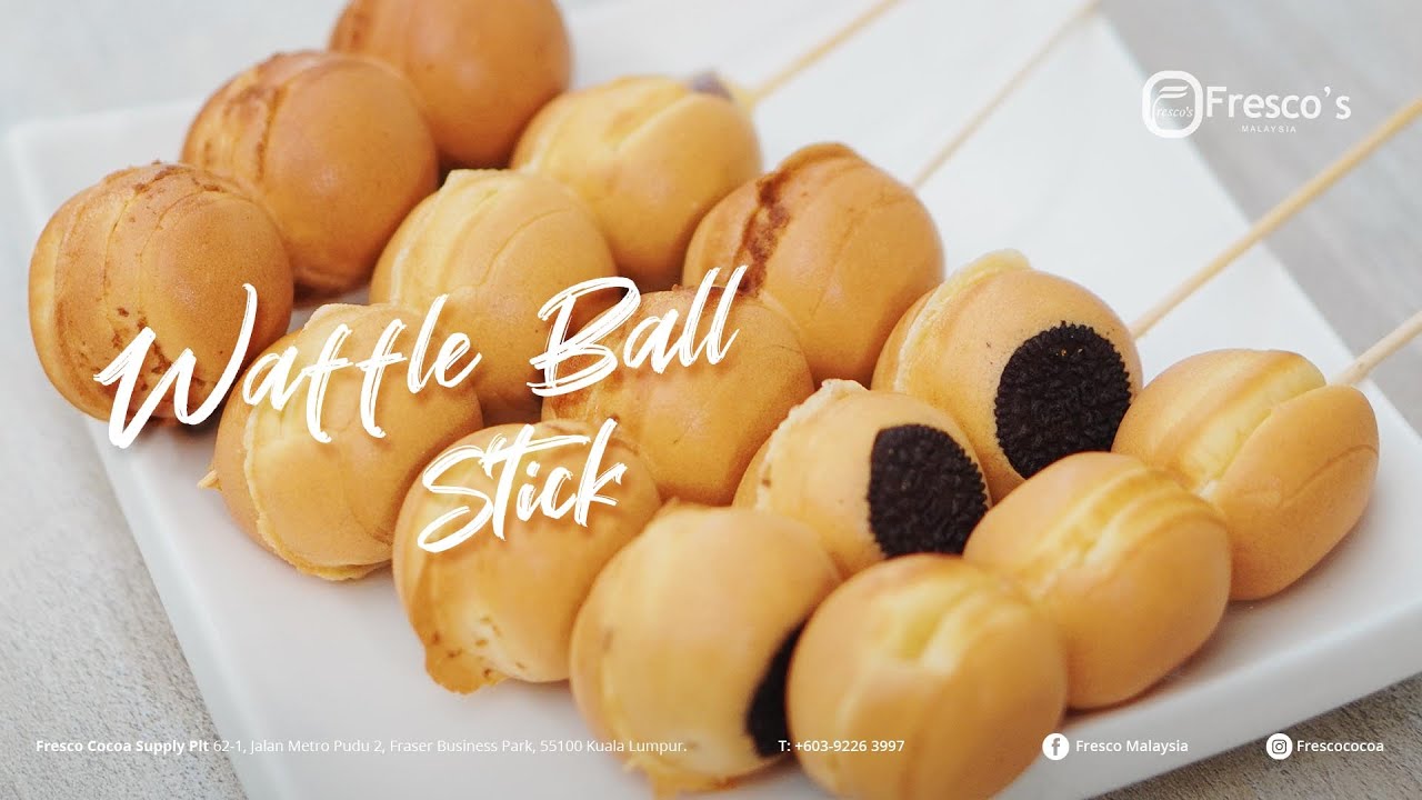 A white plate holds several skewers of crispy waffle balls, some with a chocolate cookie layer, displayed for serving.