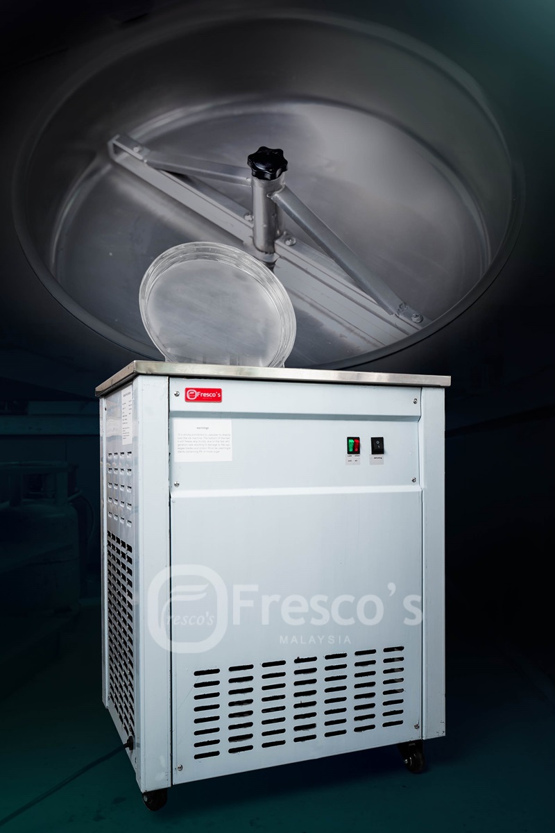 A commercial fried ice cream machine with control buttons and vents, branded "Fresco's Malaysia," stands against a dark background—ideal as an ice cream and sorbet maker for dessert shops.